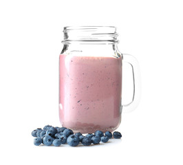 Mason jar with tasty smoothie and blueberries on light background