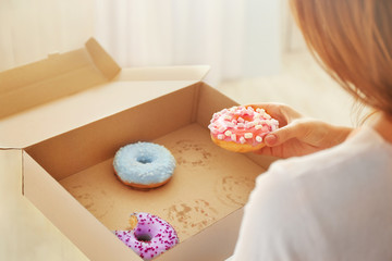 Woman taking tasty donut from carton box, close up view
