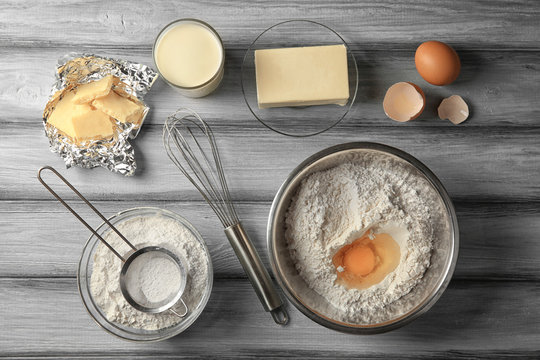 Ingredients for making cake on grey wooden background, top view