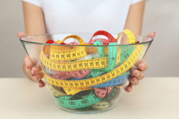 Woman holding bowl with measuring tape on white  background