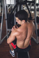 Young attractive adult man exercising and doing weight lifting at fitness gym. Sport training indoors.