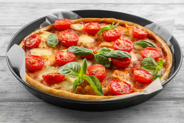 Baking dish with fresh tasty pizza Margarita on wooden background