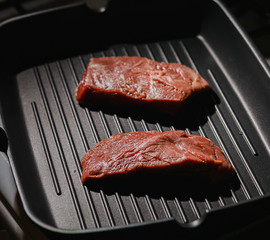 Raw uncooked beef beef steaks on grill pan background. Top view with filter and grain for vintage film effect