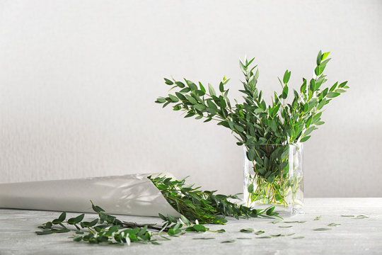 Green eucalyptus branches in vase and paper wrap on table