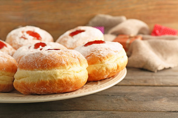 Plate with tasty donuts on wooden background, close up. Hanukkah celebration concept