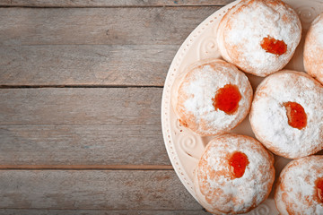 Plate with tasty donuts on wooden background. Hanukkah celebration concept