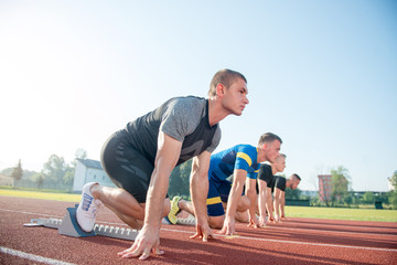 Close-up side view of cropped people ready to race on track field