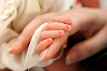The baby clings to his mother's finger