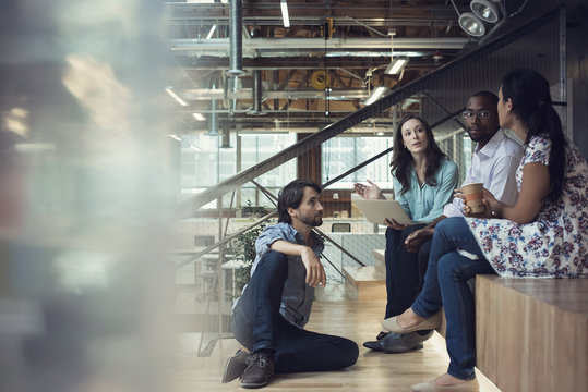Young business people discussing, sitting on stairs