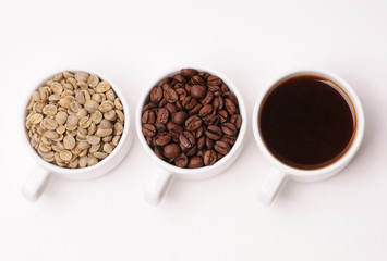 Three white cups with different stages of coffee: green and roasted beans and ready drink