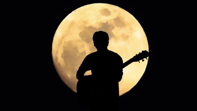 Man playing guitar with full moon on background