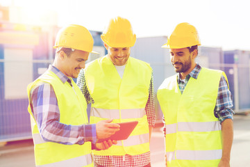 smiling builders in hardhats with tablet pc