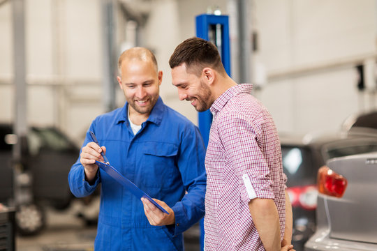 auto mechanic with clipboard and man at car shop