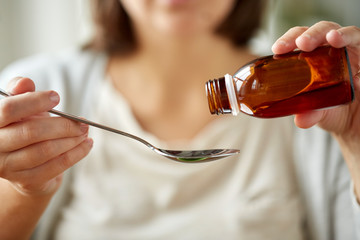 woman pouring medication from bottle to spoon