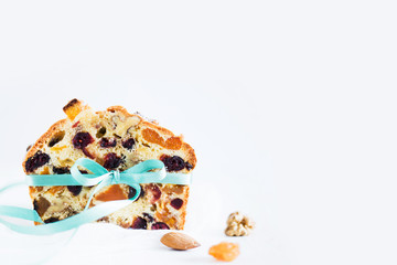 Homemade cake with dried fruits and nuts  with turquoise bow on white table. Christmas traditional german stollen. Tasty food. 
