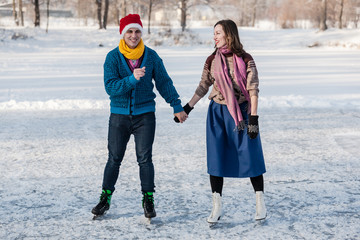 Happy couple having fun ice skating on rink outdoors.