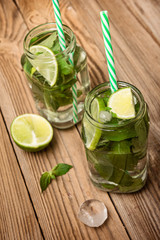 Glasses with mojito, mint, lime and  ice on wooden background