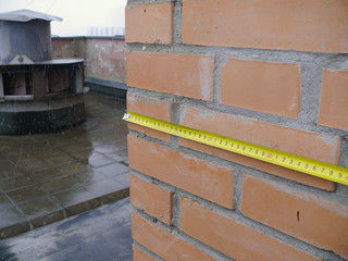 measuring the size of a brick wall on a building roof
