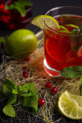 Refreshing drink with lime, mint and cranberries on a dark background