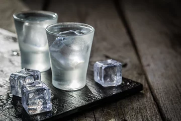 Foto op Plexiglas anti-reflex Wodka in borrelglaasjes op rustieke houten achtergrond © anaumenko