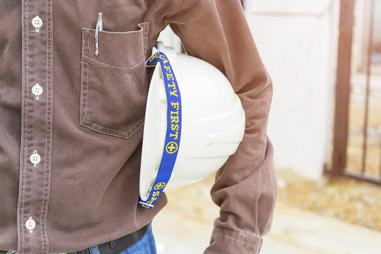 Civil engineer holding white helmet in front of the building, carry safety helmet, safety first