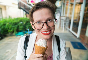 Happiness and euphoria. Funny girl looking into the camera and eats ice-cream on the street near the Italian store.