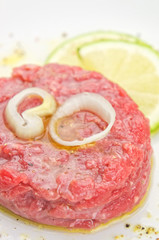 Steak tartare closeup  with lemon slices on white plate