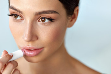 Beautiful Woman With Beauty Face Applies Balm On Lips. Skin Care