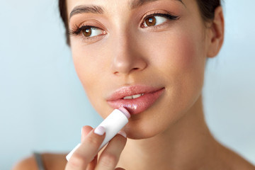 Beautiful Woman With Beauty Face Applies Balm On Lips. Skin Care - obrazy, fototapety, plakaty
