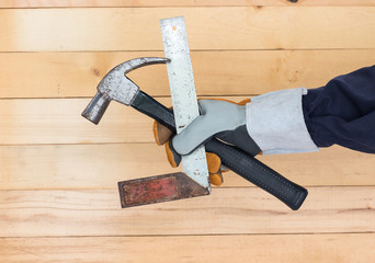 Fototapeta na wymiar Hand in glove holding iron ruler and hammer