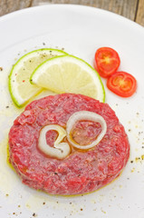 Steak tartare closeup  with lemon slices on white plate