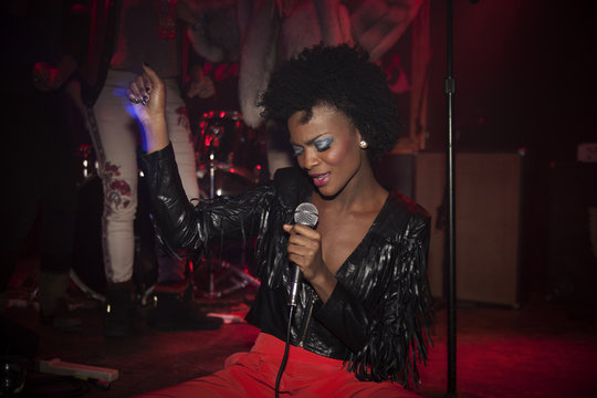 Young woman singing karaoke in nightclub
