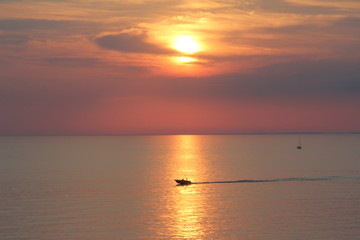silhouettes of boats, yachts, ship on the background of sunset, sunrise, yellow, orange sky at sea
