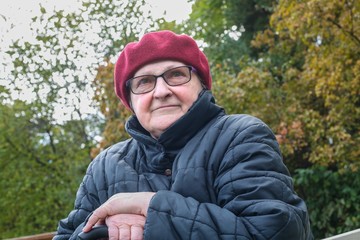 пожилая женщина сидит и отдыхает в осеннем парке © yulanaom