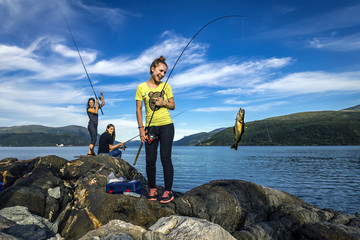 Young people are fishing on the rocks next to the fjord, Norway - 127417789