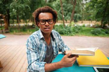 Handsome african young man reading and learning in outdoor cafe