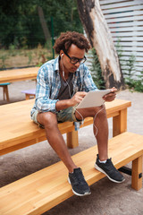 Concentrated man using earphones and tablet in patk