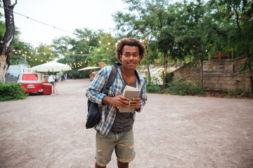 Obraz premium Happy african young man holding backpack and books