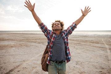 Happy man with raised hands standing on the beach