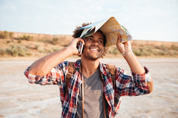 Man covered head with map and talking on cell phone