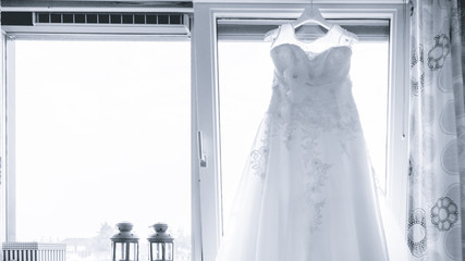 White Wedding dress hang  near window, before dressing ceremony