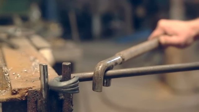 Close-up blacksmith shapes the metal manually