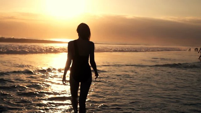 Young woman walking into sea during sunset, super slow motion 240fps
