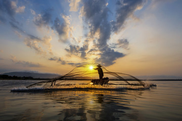 Fisherman throwing fishing net in the sunrise