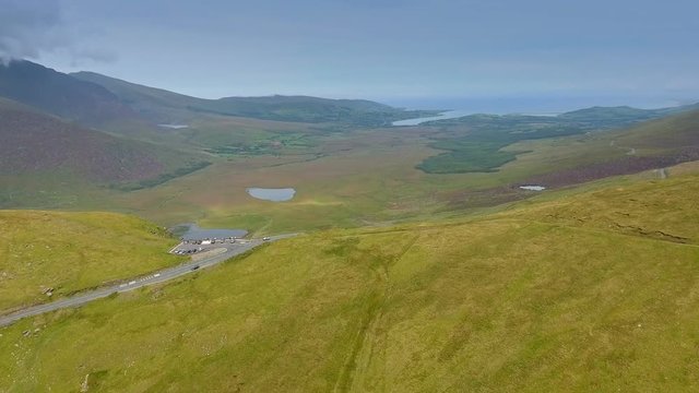 The aerial view of the mountain on the top of the Skyroad with cars parked on the parking lot watching the view in Ireland