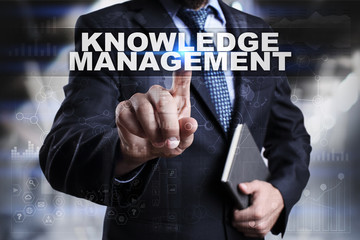 Businessman is pressing button on touch screen interface and selecting knowledge management.
