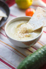 Hummus in traditional bowl with oil, spices and vegetables. Nice vegetarian hummus