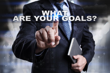 Businessman is pressing button on touch screen interface and selecting what are your goals.