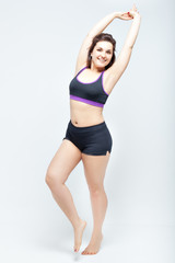 Fototapeta premium Portrait of beautiful smiling plump woman in a sports underwear on a white background