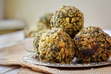Five falafel balls on metal plate over sackcloth.